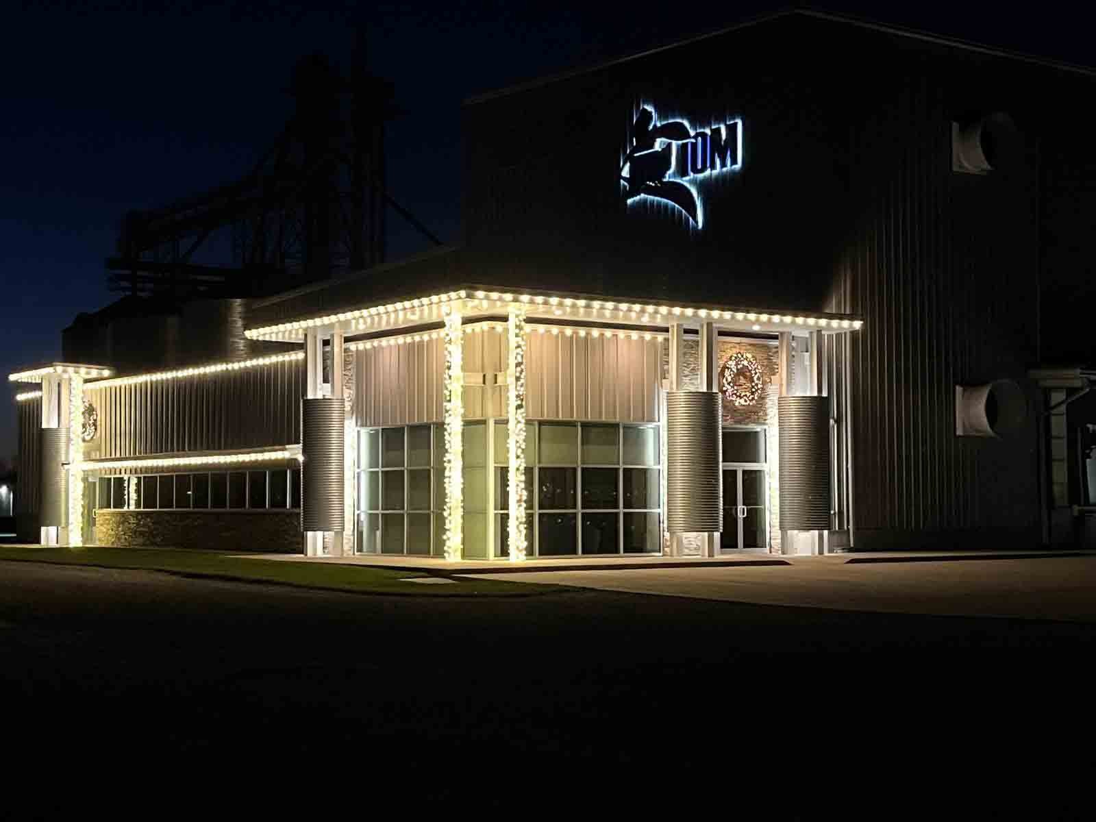 Commercial building in Indiana with warm white Christmas lights along the roofline and garland wrapped up every entrance column